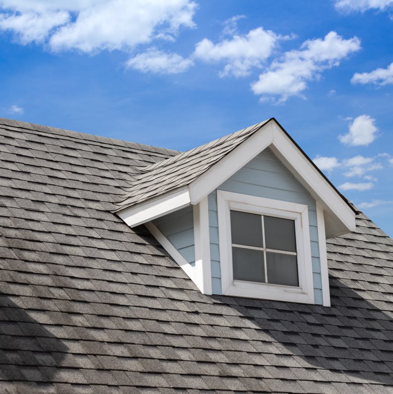 Image of a residential home with asphalt roofing and cloudy blue sky's in the background
